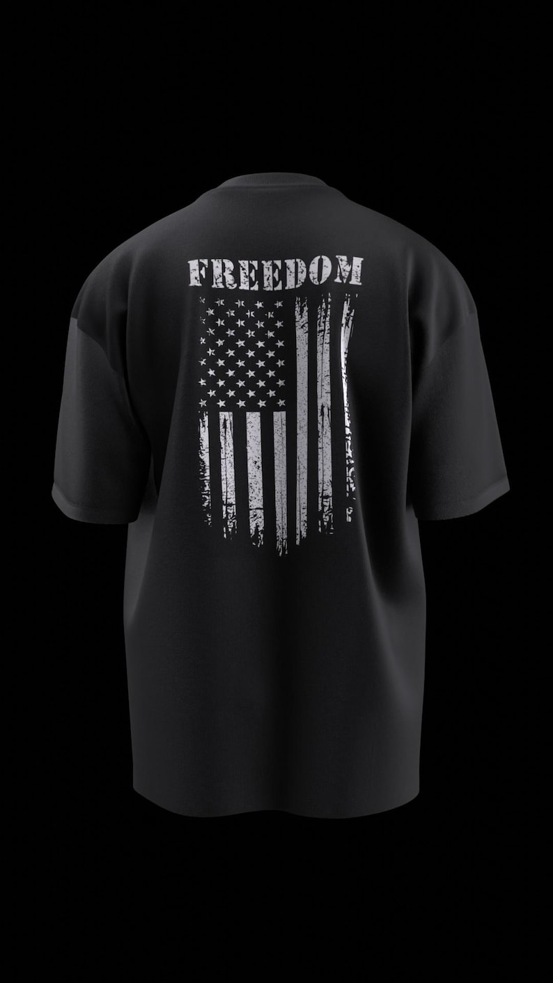 May include: Black t-shirt with a distressed white American flag graphic on the back. The word "FREEDOM" is printed above the flag. The shirt has short sleeves and a relaxed fit.