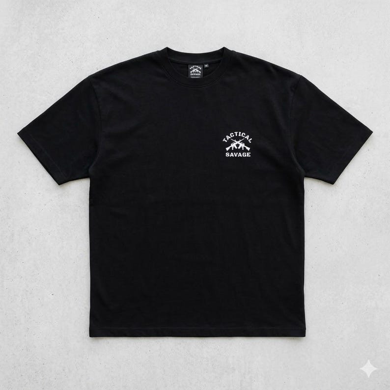 May include: Black t-shirt with a white graphic on the chest that reads "TACTICAL SAVAGE" above two crossed rifles. The shirt has a crew neck and short sleeves. The shirt is made of a soft material.
