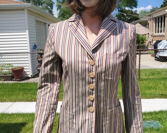 May include: A striped blazer with a beige, blue, red, and white color scheme. The blazer has a notched collar, long sleeves, and a button closure. The buttons are a light brown color.