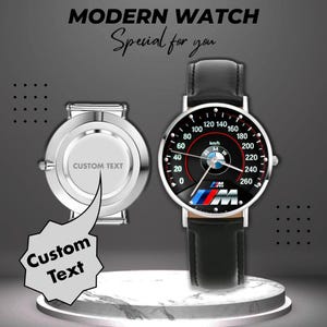 May include: A modern watch with a black face featuring a speedometer design, the BMW logo, and a black leather strap. The watch face displays numbers and markings in white. The watch is displayed next to a silver watch back with the text "CUSTOM TEXT".
