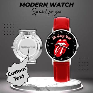 Könnte beinhalten: Eine moderne Uhr mit schwarzem Zifferblatt mit dem Rolling Stones-Logo und rotem Lederarmband. Die Uhr hat ein silbernes Gehäuse und eine zweite Uhr mit Platz für individuellen Text. Der Text "MODERN WATCH" und "Special for you" ist enthalten.