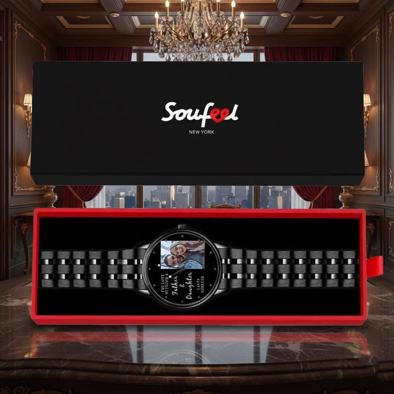May include: A black wristwatch with a photo on the face, presented in a black box with a red interior. The watch band is black and metallic. The watch face has the words "Father & Daughter Forever" and the brand name "Soufeel" is on the box.