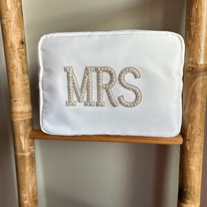 May include: White satin pillow with the word "MRS" spelled out in pearl beads.