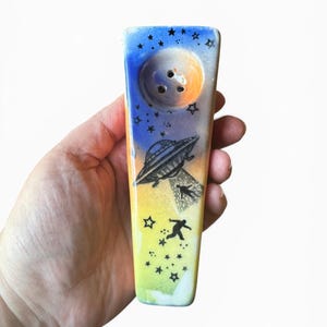 May include: A set of three ceramic mugs with a speckled, matte finish. The mugs are in shades of cream, light gray, and dark gray. Each mug has a simple, minimalist design, perfect for coffee or tea.