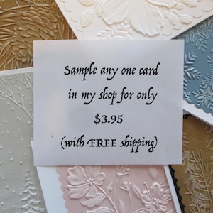 May include: A collection of rectangular greeting cards featuring various embossed designs including pinecones, snowflakes, floral patterns, and winter forest scenes in shades of brown, white, blue, and pink with scalloped edges on some cards.