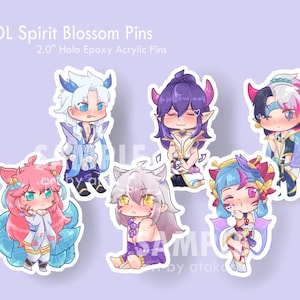 May include: Six 2.0 inch holographic epoxy acrylic pins featuring characters from the video game League of Legends. The characters are depicted in a chibi style with colorful outfits and accessories. The pins are designed with a white border and a glossy finish.