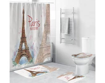 May include: A bathroom set with a white shower curtain featuring a watercolor illustration of the Eiffel Tower with the word "Paris" and the text "Your Text Here". The set also includes a toilet seat cover and two bath mats with the same Eiffel Tower design.