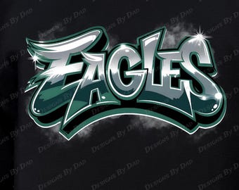 May include: Black sweatshirt featuring the word "EAGLES" in a stylized, 3D design with silver, green, and white accents. The text has a graffiti-style aesthetic, with a shadow effect. The sweatshirt is a crew neck.