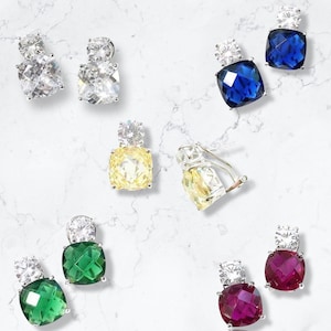 May include: Assortment of earrings with various colored gemstones, including blue, green, yellow, and red. Each earring features a square-shaped gemstone with a smaller clear gemstone on top.