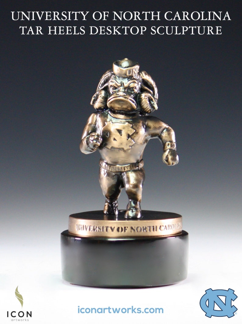 Puede incluir: Una escultura de bronce de la mascota de los Tar Heels de la Universidad de Carolina del Norte, un carnero, que lleva una camiseta con las letras "UNC" en el sombrero y "N.C." en el pecho. La escultura est&aacute; sobre una base negra con las palabras "University of North Carolina" inscritas en la base.