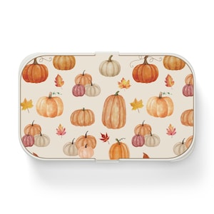 May include: A rectangular lunch box with a light beige background featuring a repeating watercolor pattern of orange, white, and muted pink pumpkins interspersed with small, colorful autumn leaves in shades of yellow, orange, and red.