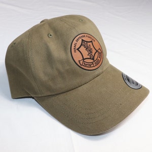 May include: A green baseball cap with an embroidered patch featuring the Israel Defense Forces logo. The logo is a star with a branch of olive leaves inside, surrounded by the text "Israel Defense Forces" in English and Hebrew.