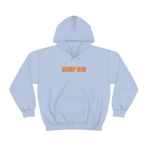 Puede incluir: Una sudadera con capucha azul claro con el texto "DUMP HIM" impreso en naranja en la parte delantera.