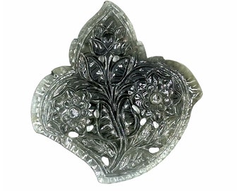 May include: A carved gray gemstone pendant in the shape of a leaf with intricate floral designs.