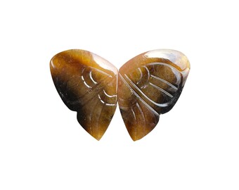 May include: A carved butterfly figurine with a natural, earthy color palette. The wings are a blend of brown and amber, with intricate carved details. The butterfly is symmetrical and appears to be made of stone or a similar material.