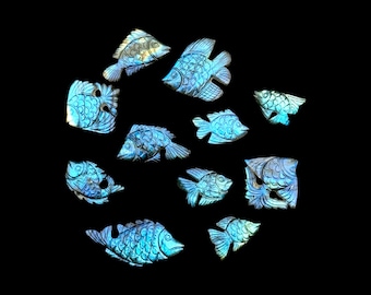 May include: A collection of ten iridescent labradorite gemstone carvings shaped like fish. Each piece features intricate scale detailing and displays a shimmering blue and gold labradorescence across the surface of the stone material.