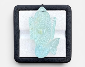 May include: A light blue carved gemstone mermaid pendant, displayed in a black box with a white interior. The mermaid has detailed features, including flowing hair, a crown, and a fishtail. The pendant is a unique piece of jewelry.