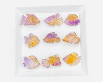 May include: Nine small fish-shaped carvings arranged in a three-by-three grid. Each piece is crafted from translucent stone featuring a gradient of yellow and purple hues, with detailed etched lines representing fins, scales, and eyes on the surface.