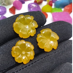 May include: Three yellow flower-shaped cabochons made of agate. The cabochons are smooth and polished.