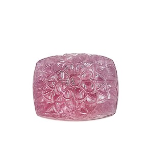 May include: A carved pink gemstone with a floral design. The gemstone is rectangular and has a smooth, polished surface.