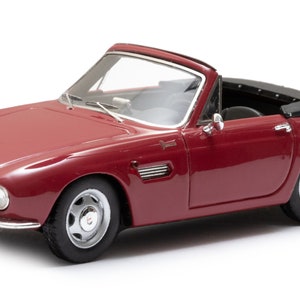 May include: A burgundy convertible car model with a black convertible top. The car has silver wheels and a license plate that reads "47474-BZ". The car is a vintage model.