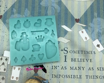 May include: A teal blue silicone mold with 14 different shapes, including a teapot, a crown, a key, a bottle, a heart, and playing card suits. The mold is on a background with a quote from Alice in Wonderland: "Sometimes I believe in as many as six impossible things before breakfast."