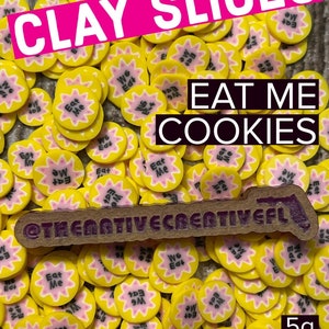 May include: A close-up of a collection of yellow and pink clay cookie slices with the text "Eat Me" and "We Eat" on them. The clay slices are arranged in a random pattern and are 5 grams in weight. The text "CLAY SLICES" and "EAT ME COOKIES" is visible in the image.