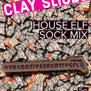 May include: A close-up of a pile of small clay house elf sock ornaments. The ornaments are in the shape of a house elf with a striped sock on its foot. The ornaments are a mix of white, gray, red, and green. The text "CLAY SLICES HOUSE ELF SOCK MIX" is written in pink and black letters on the top of the image. The text "@THENATIVE CREATIVE ELF" is written in black letters on a brown wooden sign at the bottom of the image. The text "5g" is written in black letters on a white background in the bottom right corner of the image.