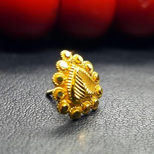 May include: A gold nose ring with a heart-shaped design and intricate detailing. The ring is made of a delicate metal and has a polished finish.