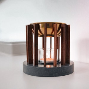 Op de afbeelding: Een houten en messing wierookbrander met een ronde, gouden kom en een glazen kaarshouder. De brander staat op een grijze stenen basis.