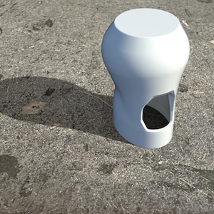 Könnte beinhalten: Weißer Keramikhocker mit einem einzigartigen, gedrehten Design und einem Ausschnitt an der Seite. Der Hocker hat eine glatte, abgerundete Oberseite.