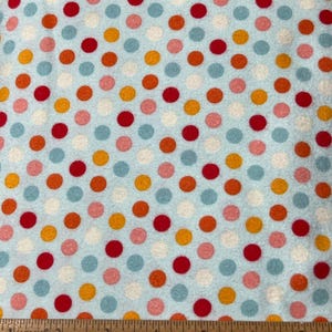 May include: A blue fabric with a repeating pattern of colorful polka dots. The dots are red, orange, pink, and light blue.