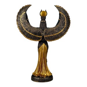 May include: A gold and black statue of the Egyptian goddess Isis with outstretched wings. The statue is standing on a base with intricate details.