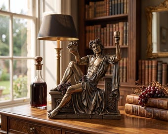 May include: A bronze-toned statue of a seated figure wearing a grape vine wreath, holding a pitcher and a goblet. The base of the statue features the name DIONYSUS. The figure is draped in fabric and positioned on a rectangular pedestal.