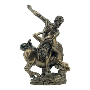 May include: Bronze sculpture depicting a muscular man wrestling a centaur. The man is positioned atop the centaur, raising an object in his right hand. The sculpture is mounted on a rocky base.