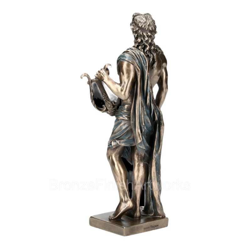 Puede incluir: Una estatua de tono bronce de una figura con cabello largo y rizado, de pie sobre una base rectangular. La figura est&aacute; envuelta en una prenda de tela con detalles azules y sostiene una lira en una mano. El texto BronzeFinishArtworks es visible.