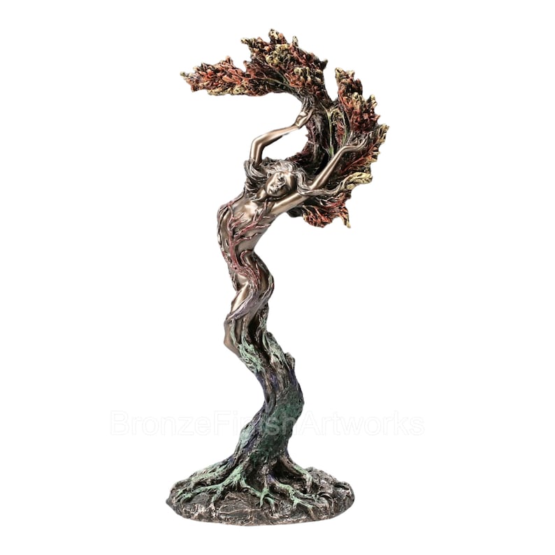 May include: A bronze-toned sculpture depicting a figure merging with a tree, featuring roots at the base, a trunk-like torso, and branches forming a canopy above. The finish includes highlights of copper, green, and dark brown throughout the piece.