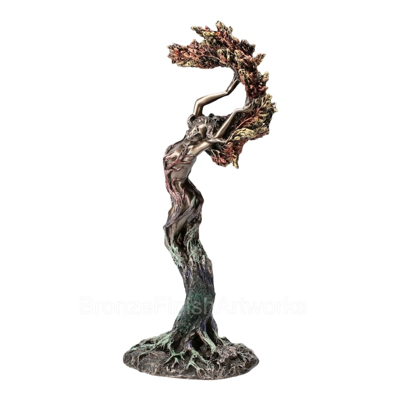May include: A bronze-finished sculpture depicting a human figure merging with a tree. The base shows exposed roots, transitioning into a textured trunk that forms the torso, with arms reaching upward to support a canopy of multi-colored autumn leaves.