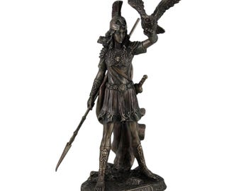 Può includere: Scultura in bronzo di Atena, la dea greca della saggezza e della guerra, che tiene un gufo nella mano destra e una lancia nella sinistra. Indossa un elmo e un'armatura, e il suo nome è inciso sulla base.