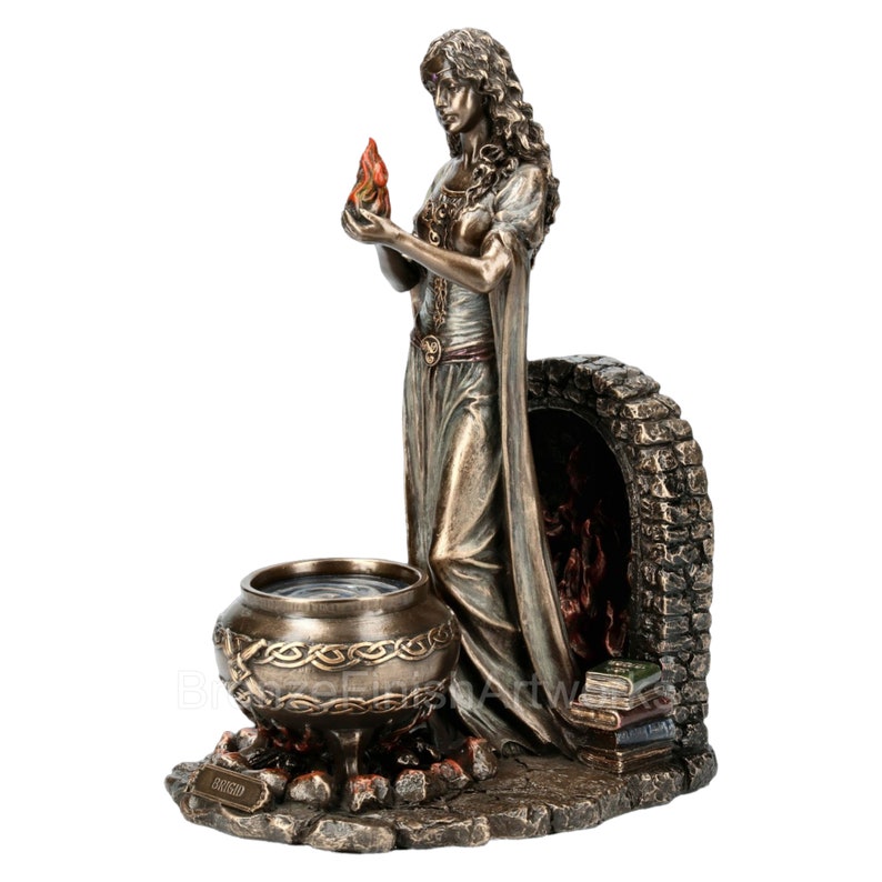 Puede incluir: Estatua de bronce de una mujer sosteniendo una llama, de pie junto a un caldero y una chimenea de piedra. La estatua est&aacute; sobre una base con libros y un dise&ntilde;o de nudo celta.