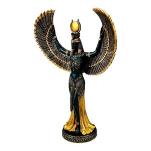 May include: A black and gold statue of the Egyptian goddess Isis with outstretched wings. She is wearing a golden crown and a flowing robe.
