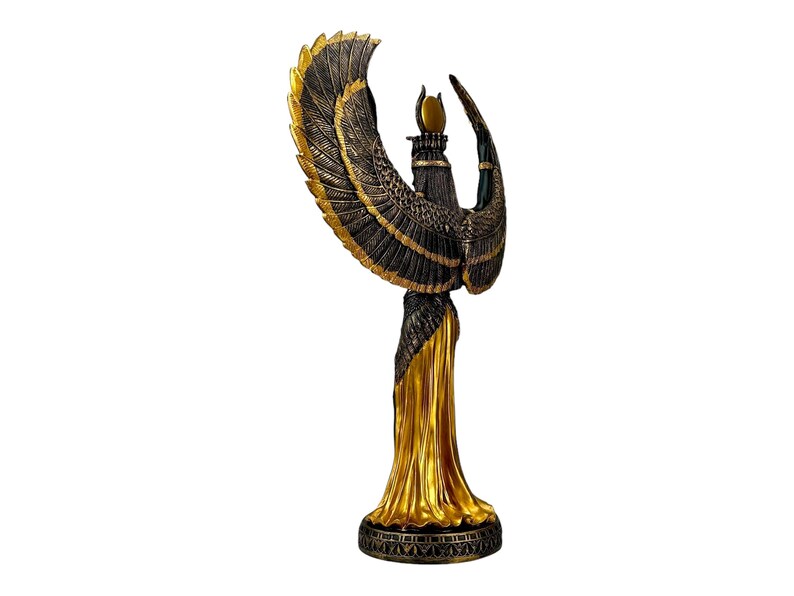 May include: A gold and black statue of the Egyptian goddess Isis with outstretched wings. The statue is standing on a base with intricate details.