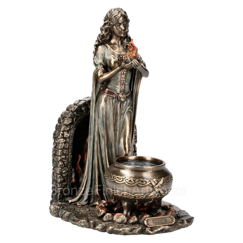 Puede incluir: Una estatua de bronce de la diosa celta Brigid sosteniendo una llama en sus manos. Ella se encuentra frente a una chimenea de piedra con un caldero sobre un fuego frente a ella. La base de la estatua est&aacute; inscrita con el nombre "Brigid".