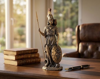 May include: A bronze-toned statue of the goddess Athena standing on a base labeled ATHENA. The figure wears a crested helmet and armor, holds a tall spear in the right hand, and carries a round shield in the left, with a small owl perched on the shoulder.