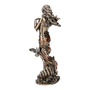 May include: Bronze sculpture of a woman with flowing hair and a flowing robe, standing on a base with waves. She is holding a dove in her hand.