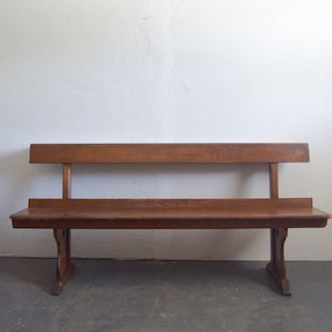May include: A wooden bench with a backrest and a lower shelf. The bench is made of dark brown wood and has a simple, classic design. The bench is approximately 60 inches long.