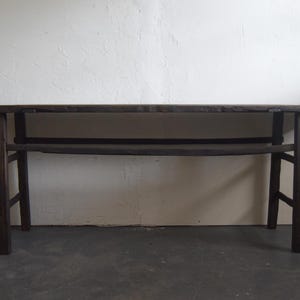 May include: A dark brown, rectangular wooden table with a lower shelf. The table has four legs and a long, flat top. The table is approximately 60 inches long.