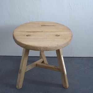 May include: A round wooden stool with three legs. The stool is made of natural wood and has a rustic look.