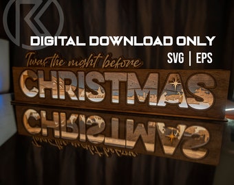 Könnte beinhalten: Ein Holzschild mit den Worten "Twas the night before Christmas" und einer Darstellung der Weihnachtsgeschichte. Das Schild spiegelt sich in einer dunklen Oberfläche.