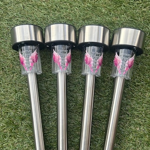 May include: Four silver solar-powered lights with pink angel wings and the text "Forever an Angel in Heaven,  Gathered with the Angels,  Mum" on each glass cylinder.